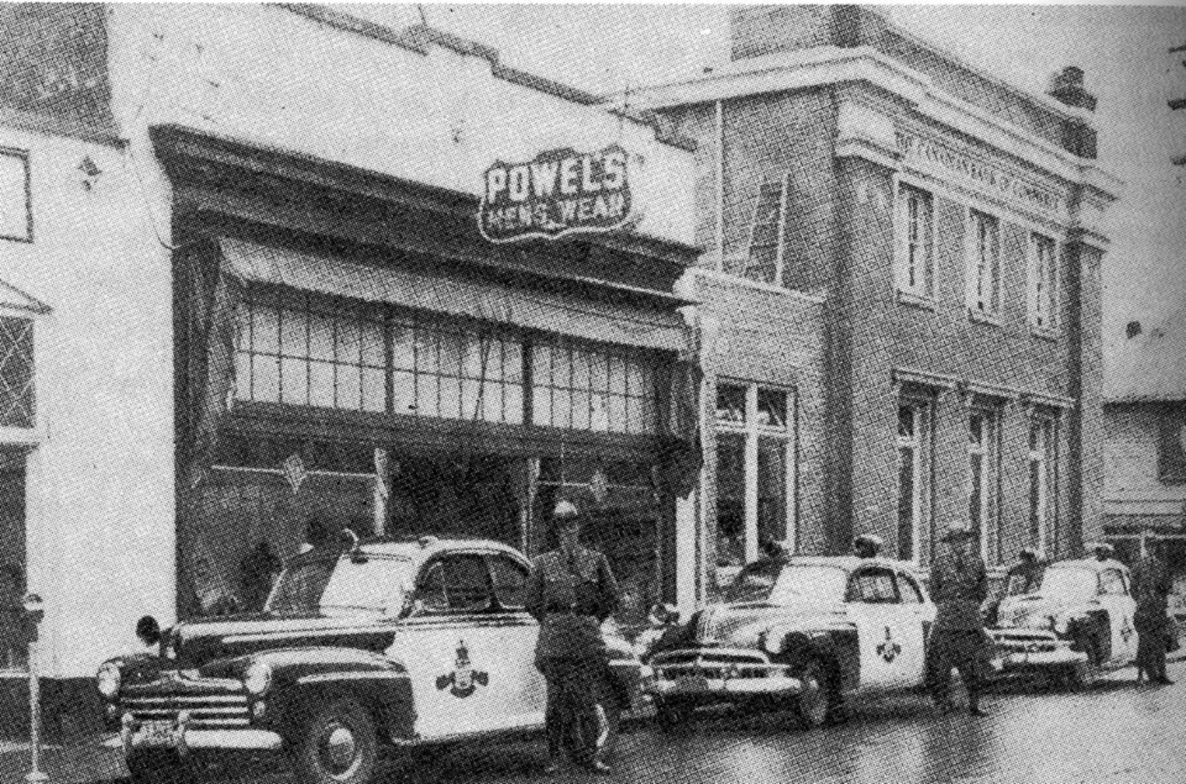 45 Craig Street as Powel's Men's Wear, circa 1950, with B.C. Provincial Police officers in front. The building on the right was the Canadian bank of Commerce, now demolished. The CIBC branch now stands on that site. (Note: we are currently checking for the source of this photo)